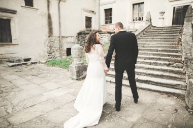 Güzel, romantik bir düğün. Yeni evliler. Eski kalenin yakınlarında sarılıyorlar.