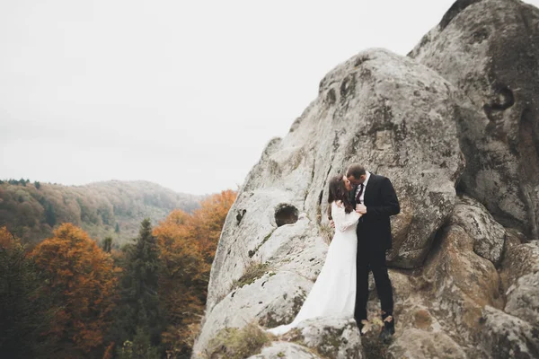 Güzel dağlarda poz veren mutlu bir düğün çifti.