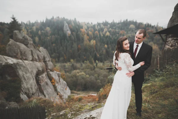 Joyeux beau couple de mariage mariée et marié le jour du mariage à l'extérieur sur le rocher des montagnes. Couple mariage heureux en plein air sur la nature, douces lumières ensoleillées — Photo