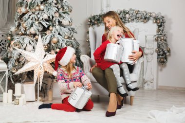 Anne ve kızları küçük kızların doğum günü hediyelerini açıyorlar.