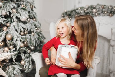 Mutlu Noeller ve mutlu tatiller. Neşeli anne ve tatlı kızı hediye değiş tokuşu yapıyor.