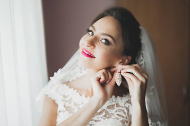 Cüppeli muhteşem gelin bir odada düğün töreni için poz veriyor ve hazırlanıyor.