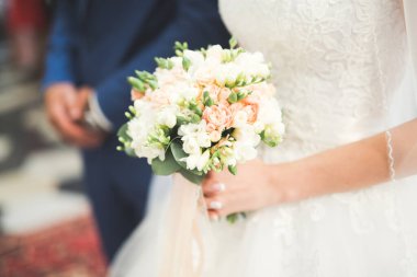 Gelin çiçekli büyük ve güzel bir düğün buketi tutuyor.