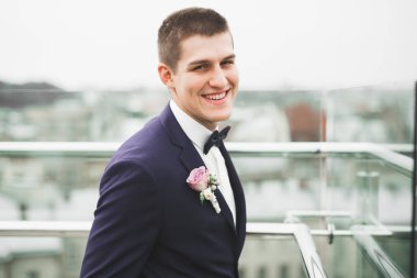 Yaka çiçeğiyle poz veren mutlu yakışıklı damat.