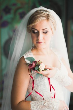 Beyaz elbiseli lüks gelin düğün törenine hazırlanırken poz veriyor.