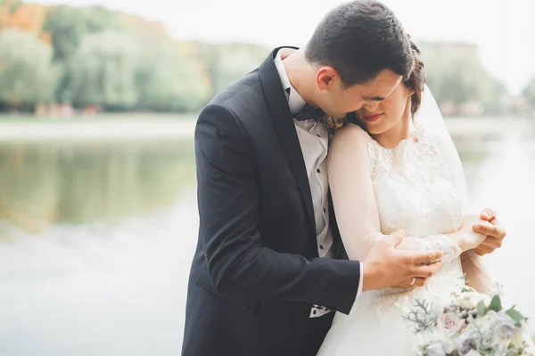 Romantisch, sprookje, gelukkig pasgetrouwd stel knuffelen en kussen in een park, bomen op de achtergrond — Stockfoto