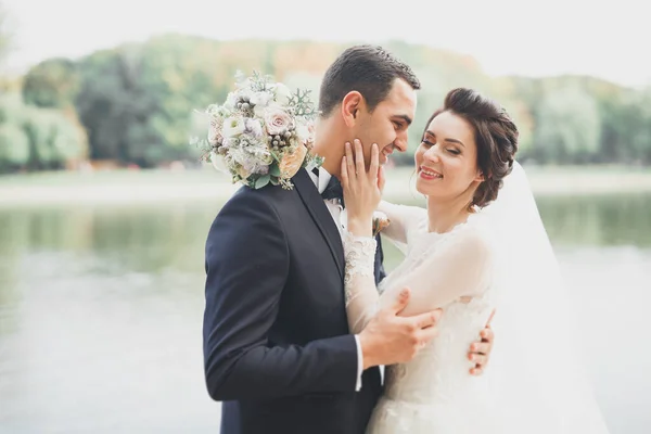 Newly married couple running and jumping in park while holding hands — Stock Photo, Image