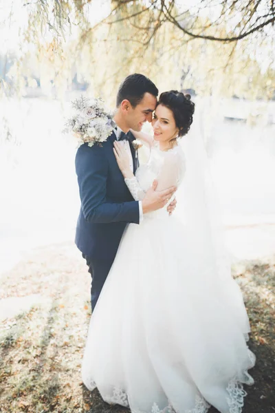 Elegante pareja de recién casados felices caminando en el parque el día de su boda con ramo —  Fotos de Stock