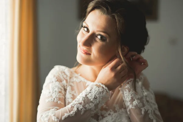 Hermosa novia con vestido de novia de moda con plumas con maquillaje de lujo deleite y peinado, estudio sesión de fotos interior — Foto de Stock