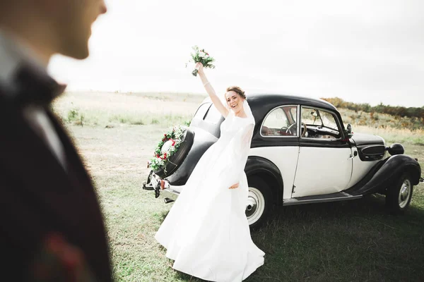 Felice coppia di sposi, uomo e moglie baciare vicino elegante auto retrò — Foto Stock