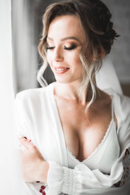 Tüylü, lüks makyaj, saç stili, stüdyo içi fotoğraf çekimi olan güzel bir gelin.