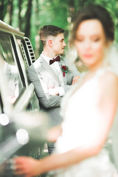 Vackra nygifta par poserar nära retro bil — Stockfoto