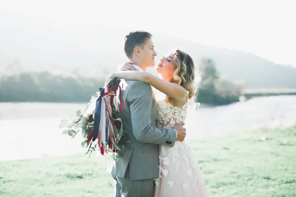 Hochzeitspaar, Bräutigam und Braut umarmen sich, im Freien am Fluss — Stockfoto