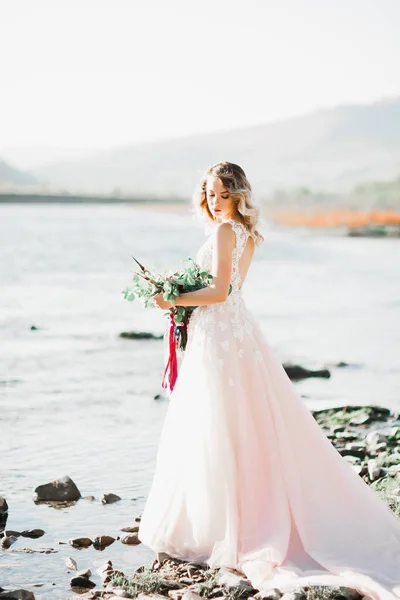 Bella sposa di moda in abito da sposa posa vicino al fiume — Foto Stock