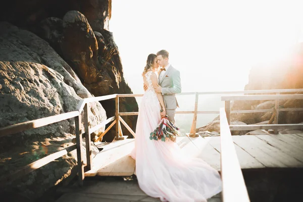 Güzel bir düğün çifti mükemmel bir manzarayla dağda öpüşüyor ve sarılıyor. — Stok fotoğraf