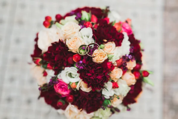 Schöne getönte Bild mit Eheringen vor dem Hintergrund eines Straußes von Blumen — Stockfoto