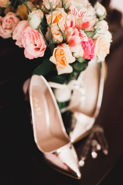 Brides wedding shoes and costume jewellery with a bouquet with roses and other flowers. — 스톡 사진