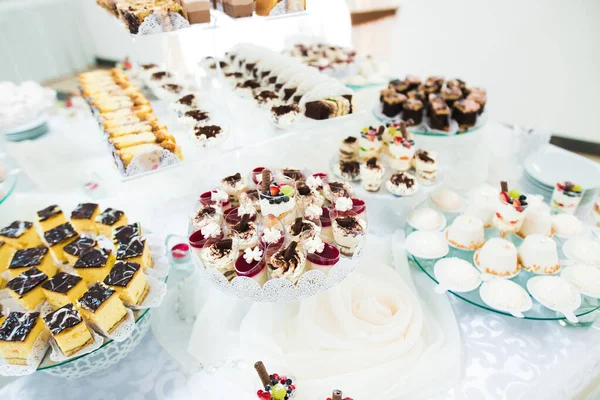 Deliciosa e saborosa mesa de sobremesa com cupcakes e tiros no closeup da recepção — Fotografia de Stock