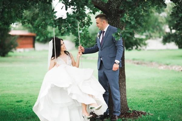 Hombre empujando a su esposa recién casada en un columpio — Foto de Stock