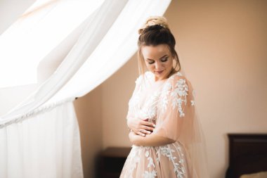 Cüppeli muhteşem gelin bir odada düğün töreni için poz veriyor ve hazırlanıyor.