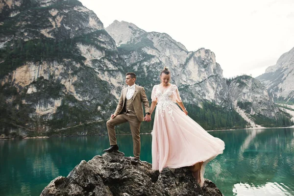 イタリアのKarersee湖の近くの若いカップル。湖の石で手を握る — ストック写真