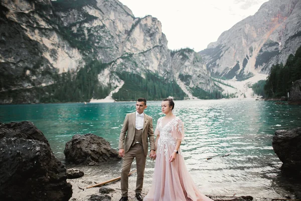 Pareja joven cerca del lago Karersee, Italia. Tomando de la mano en la piedra en el lago —  Fotos de Stock