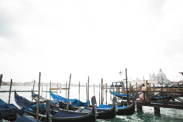 Svatební dvojice ubytovaná na mostě v blízkosti kanálu s gondolami v Benátkách, Itálie — Stock fotografie