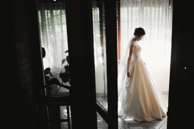 Cüppeli muhteşem gelin bir odada düğün töreni için poz veriyor ve hazırlanıyor.