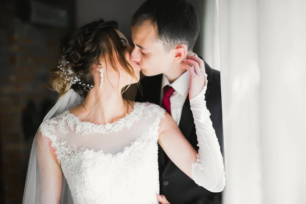 Gyönyörű menyasszony és vőlegény ölelkeznek és csókolóznak az esküvő napján. — Stock Fotó