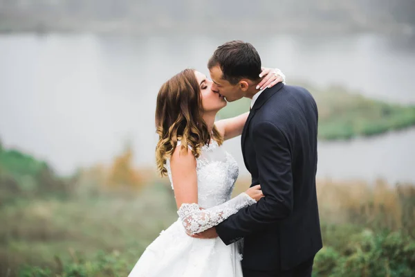 Hermosa novia y novio abrazar y besar en su boda al aire libre — Foto de Stock