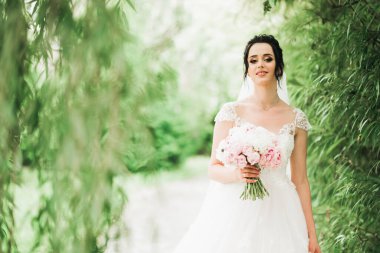 Lüks bir gelin, bir kız buketle poz veriyor ve gülümsüyor.