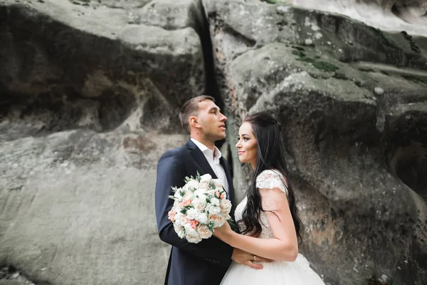 Bella giovane coppia di nozze in posa con mazzo di fiori in mano — Foto Stock