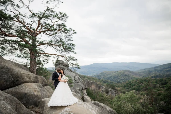 Великолепная невеста, позирующая груму и веселящаяся у гор с изумительным видом, место для текста, свадебная пара — стоковое фото
