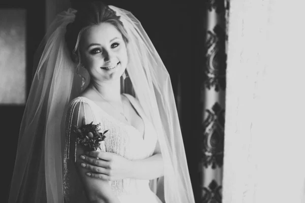 Hermosa novia de lujo en elegante vestido blanco sostiene ramo de flores en las manos — Foto de Stock