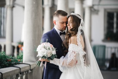 Güzel, genç bir çift ellerinde çiçeklerle poz veriyorlar.