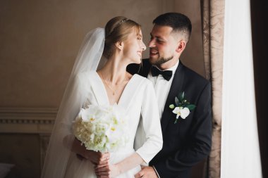 Güzel, genç bir çift ellerinde çiçeklerle poz veriyorlar.