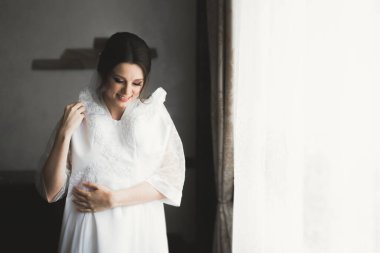 Beyaz elbiseli lüks gelin düğün törenine hazırlanırken poz veriyor.