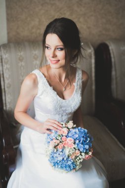 Cüppeli muhteşem gelin bir odada düğün töreni için poz veriyor ve hazırlanıyor.