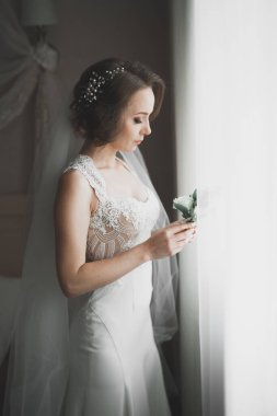 Cüppeli muhteşem gelin bir odada düğün töreni için poz veriyor ve hazırlanıyor.