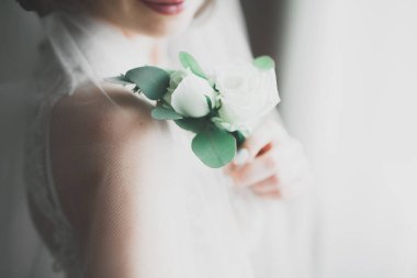 Cüppeli muhteşem gelin bir odada düğün töreni için poz veriyor ve hazırlanıyor.