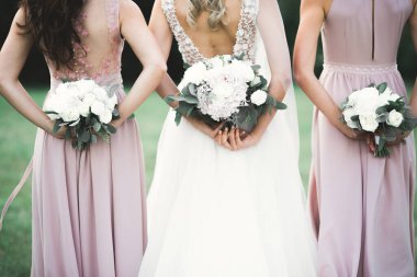 Gelin çiçekli büyük ve güzel bir düğün buketi tutuyor.