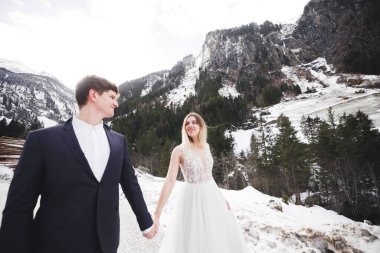 Çift, gelin ve damat dağlarda el ele tutuşuyorlar.