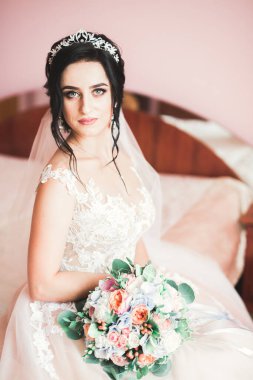 Cüppeli muhteşem gelin bir odada düğün töreni için poz veriyor ve hazırlanıyor.