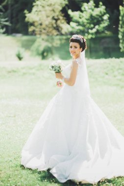 Parkta poz veren gelinlikli güzel, lüks bir gelin.