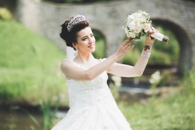 Çekici gelinin portresi, uzun saçlı, büyük buketli poz veren.