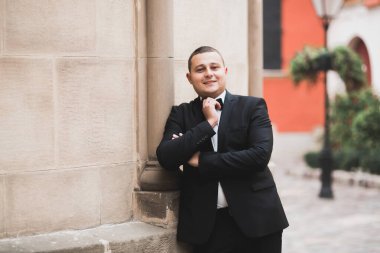 Yaka çiçeğiyle poz veren mutlu yakışıklı damat.