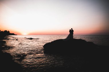 Güzel bir sahilde poz veren genç bir çiftin mutlu ve romantik sahnesi.