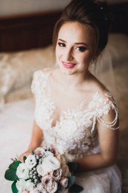 Beyaz elbiseli lüks gelin düğün törenine hazırlanırken poz veriyor.