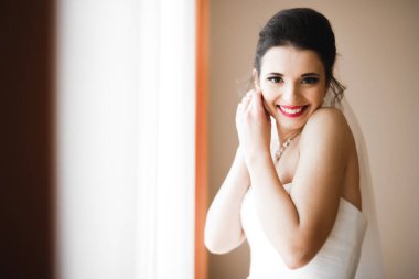 Beyaz elbiseli lüks gelin düğün törenine hazırlanırken poz veriyor.