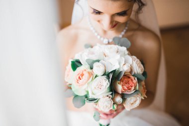 Gelin çiçekli büyük ve güzel bir düğün buketi tutuyor.